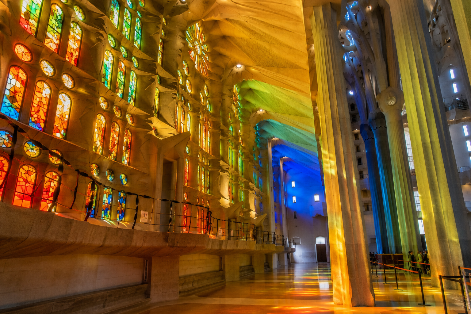 Colourful stained-glass windows inside Sagrada Familia in Barcelona casting red, orange, green and blue light across the interior.